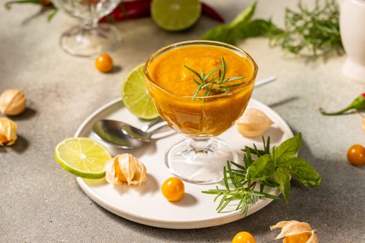 Vibrant cape gooseberry sauce, garnished with rosemary and lime, sits in a glass bowl, ready to enhance culinary creations