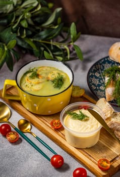 Delicious creamy soup served with croutons and fresh dill, accompanied by a cheese dip, bread, and cherry tomatoes