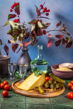 Traditional russian appetizer with vodka, cheese, pickles, and tomatoes served on a wooden board