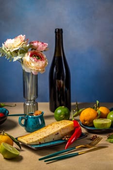 Wedge of gourmet cheese resting on a plate with chili pepper, fresh fruits, wine, and flowers, creating an elegant dining scene