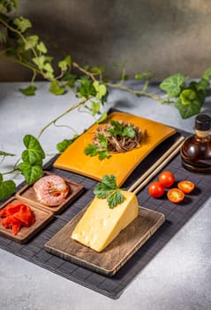 Soba noodles, cheese, shrimp, and cherry tomatoes are arranged on a table, showcasing a unique fusion of culinary traditions