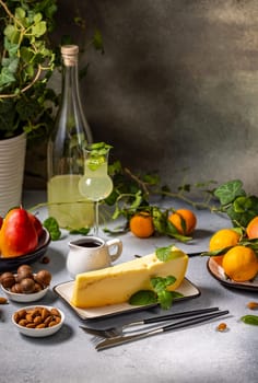 Delectable cheese wedge topped with fresh mint, paired with vibrant fruits, assorted nuts, and a glass of refreshing limoncello