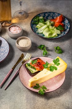 Elegant appetizer featuring smoked salmon, cucumber, and a slice of cheese served on rye bread, accompanied by fresh herbs