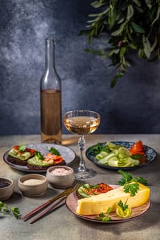 Elegant table setting featuring cheese, salmon canapés, fresh cucumber, and a glass of rosé wine, creating a sophisticated culinary experience