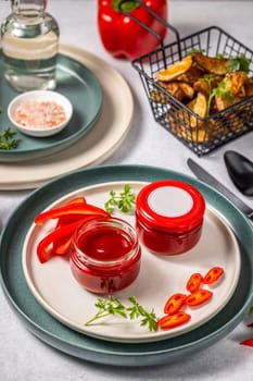 Two jars of red hot chili pepper sauce with blank labels, ready to be filled with homemade sauce, served on a plate with fresh ingredients