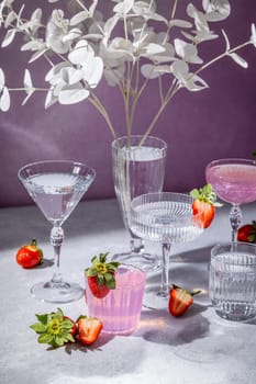 Refreshing strawberry cocktails served in crystal stemware, garnished with fresh strawberries and decorative white leaves, create an elegant scene