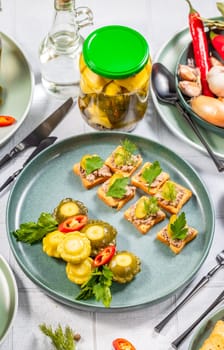 Pickled pattypan squash and canape with pate, decorated with fresh herbs, served on a festive table with pickled cucumbers