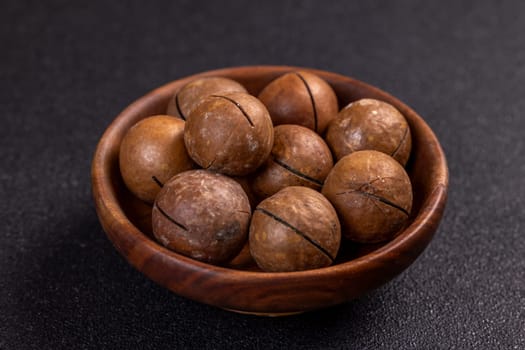Shelled macadamia nuts sitting in small wooden bowl, creating appetizing arrangement on dark background