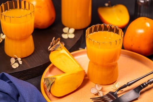 Two glasses of refreshing persimmon juice are served alongside ripe persimmon fruits, creating a vibrant and healthy table setting
