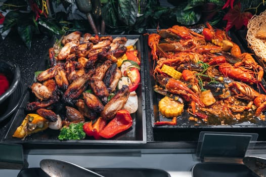 hot dishes garnish at Asian buffet in hotel restaurant for breakfast. Fried chicken meat and crayfish at the Asian night market in Vietnam