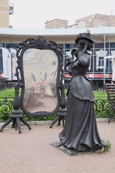 Nizhny Novgorod, Russia - August 27, 2016 - Street sculpture depicting a lady in historic attire next to a large ornate mirror