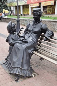 Nizhny Novgorod, Russia - August 27, 2016 - A charming sculpture shows a woman seated on a bench engaging with a child