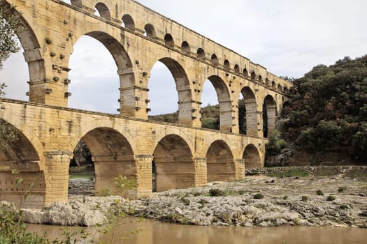 Visitors admire the impressive Roman aqueduct bridge in a scenic setting.
