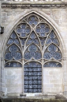 A beautiful gothic window features intricate stonework and detailed glass, located in Carcassonne.