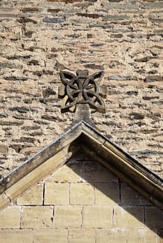 Unique stone sculpture adorns the gabled roof of a historic structure in Conques, showcasing exquisite craftsmanship.