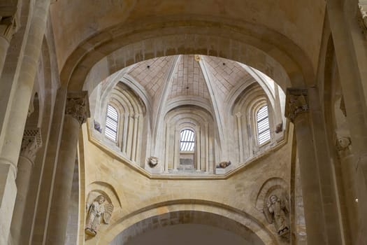 Explore the stunning interior of a Gothic church in Conques, France featuring elaborate stone arches and serene light.
