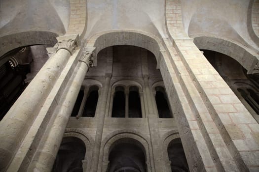 Explore the stunning interior of a Gothic church in Conques, France featuring elaborate stone arches and serene light.