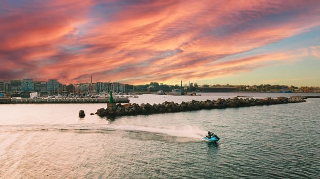 Aerial view of jet ski riding fast near the harbour at sunset. High quality photo