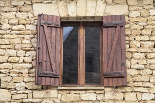 A beautifully crafted wooden window with shutters showcases the traditional architecture of Sarlat-la-Caneda, France.