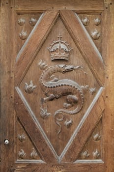 A dragon with a crown intricately carved on the wooden door of Chambord Castle shows its historical importance.