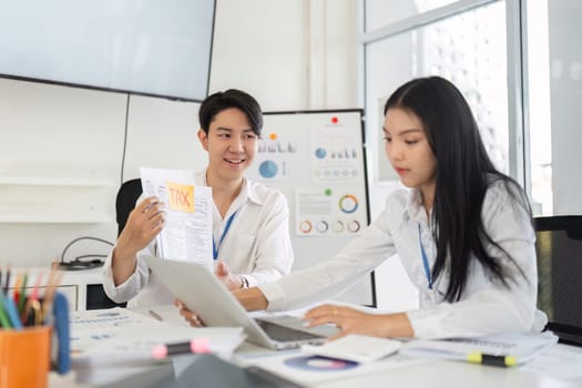 Two young professionals engage in a discussion about tax strategies, showcasing teamwork and collaboration in an office environment.