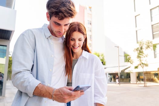man and woman smiling happy looking a cell phone together, they are enjoying the moment and sharing something on the phone, concept of technology of communication and social media, copyspace for text