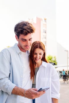 man and woman smiling happy looking a cell phone together, they are enjoying the moment and sharing something on the phone, concept of technology of communication and social media, copyspace for text