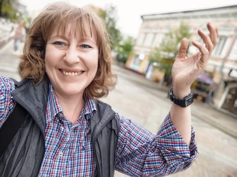 Smiling woman takes a cheerful selfie during her city excursion, enjoying travel and blogging on a delightful day.