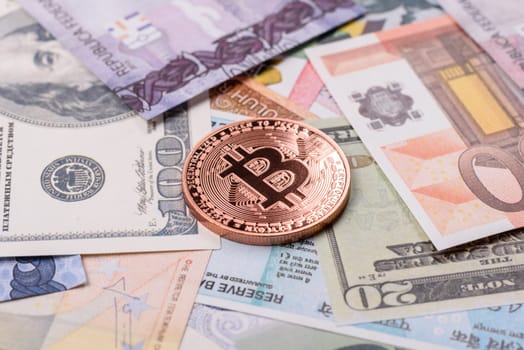 Round metal bitcoin on a background of paper banknotes of different currencies. Background for your design