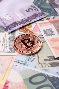 Round metal bitcoin on a background of paper banknotes of different currencies. Background for your design
