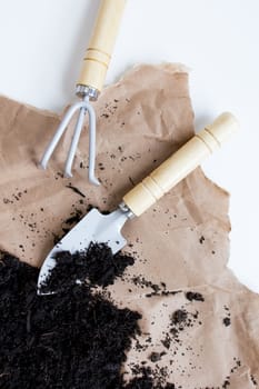 Gardening tools on brown paper with fresh soil for horticulture and planting.