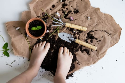 Child gardening exploration with soil and tools on craft paper.