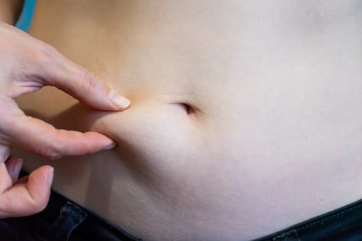 A hand gently presses against a person's abdomen, focusing on the skin and underlying tissue. This action indicates an assessment of the bodys tension and relaxation levels