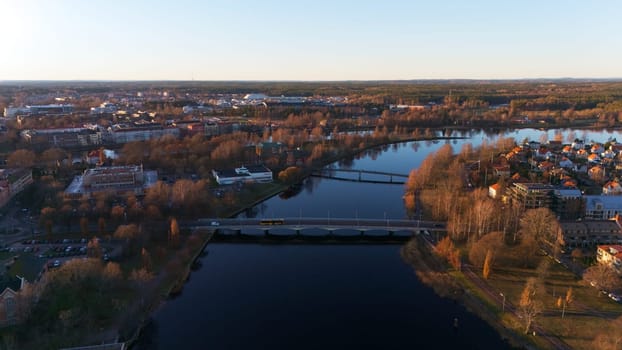 A stunning aerial view of Karlstad, Sweden, showcasing winding rivers, bridges, and golden sunset light reflecting on the water, creating a peaceful and picturesque Scandinavian landscape.
