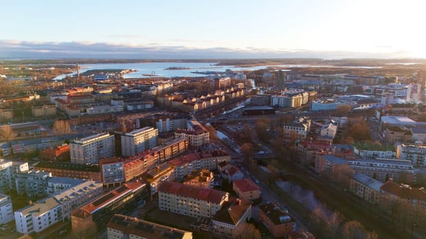 A stunning aerial view of Karlstad, Sweden, at sunset, featuring a scenic cityscape, waterfront, and golden light reflecting on buildings, creating a peaceful and picturesque atmosphere