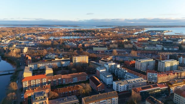 A scenic aerial view of Karlstad, Sweden, with warm sunset light illuminating the cityscape, residential buildings, and waterfront, creating a peaceful and picturesque atmosphere.