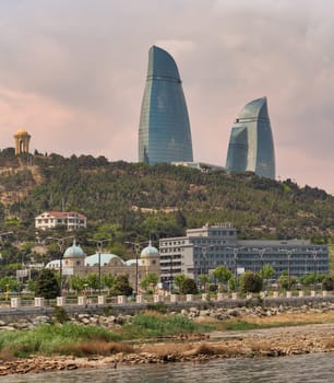 The Flame Towers, an iconic landmark in Baku, Azerbaijan, stand tall, their radiant reflections capturing sunlight as they ascend gracefully above the lush greenery and picturesque waterfront