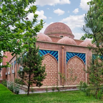 A meticulously maintained garden boasts a traditional brick wall adorned with intricate geometric patterns and colorful tiles, demonstrating architectural beauty and harmonious integration with nature