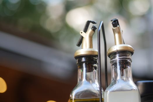 Two glass dispensers hold olive oil and vinegar at a cafe during midday.