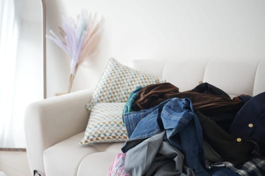 A collection of clothes piled on a couch in a stylish living room.