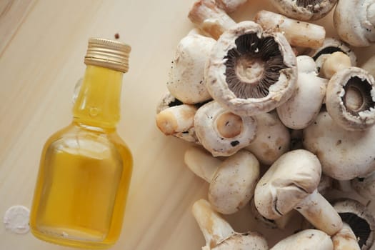 A collection of fresh mushrooms next to a small bottle of oil.