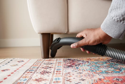 Cleaning under furniture with a vacuum in a stylish living area.