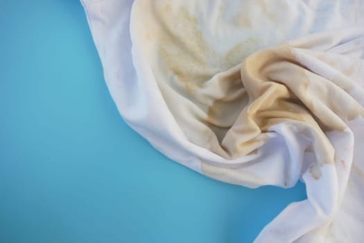 A dirty cloth with stains lies on a vibrant blue background, revealing wear.