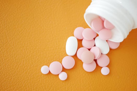 Pink and white tablets are scattered on an orange background.