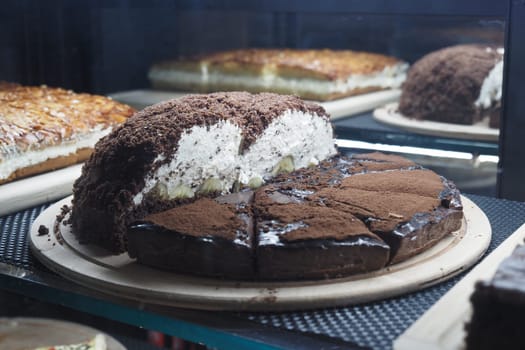 A tempting layered cake with cream and chocolate sits on display.