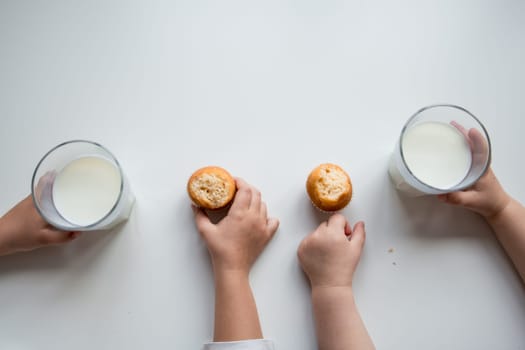 Childrens snack time with milk and muffins on white table.