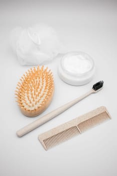 Body and hair care items on white background. Brush, comb, toothbrush, cream, loofah.