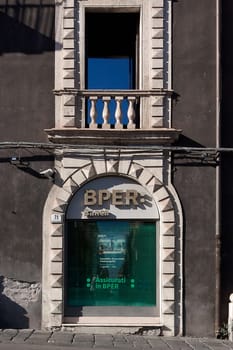 Catania. Italy - March 3, 2025: Iconic BPER Bank storefront with intricate stone design and upper balcony, reflecting a vivid blue sky. Includes modern banking signs and a security camera.