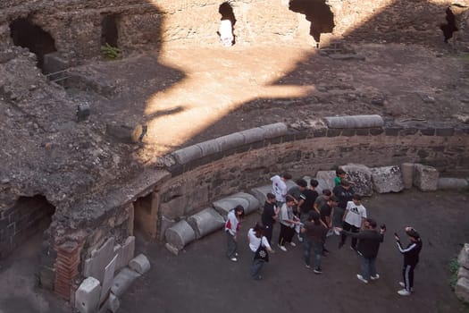 Catania. Italy - March 3, 2025: Fascinating Roman Amphitheater ruins filled with visitors amid ancient stonework. Perfect for history enthusiasts, cultural tourism, and architectural heritage shots.