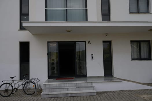 A contemporary building entrance featuring a sleek glass door and a parked bicycle on a peaceful street.